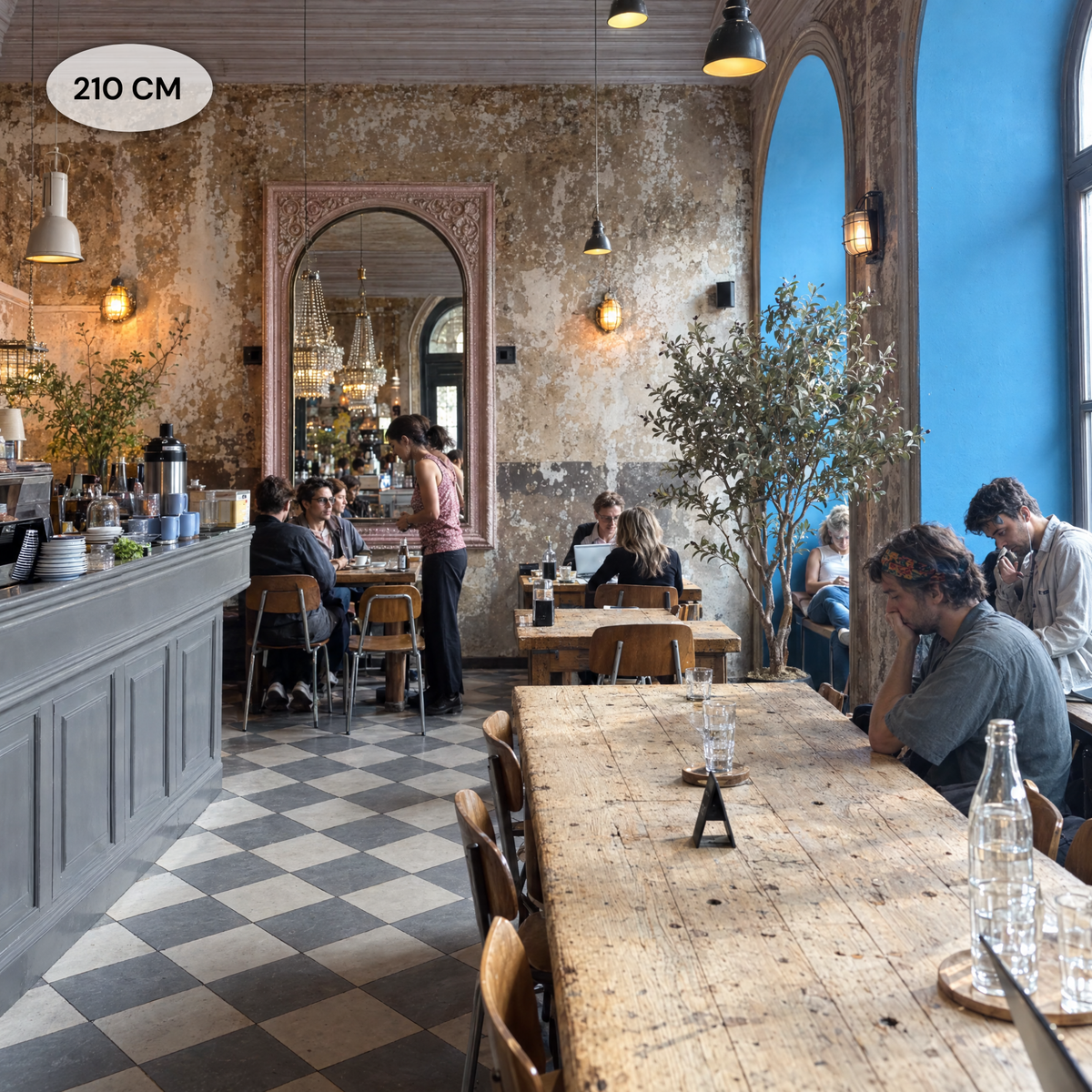 Kunst olijfboom van 210 cm als decoratie in een sfeervol café met blauwe boogramen en houten tafels