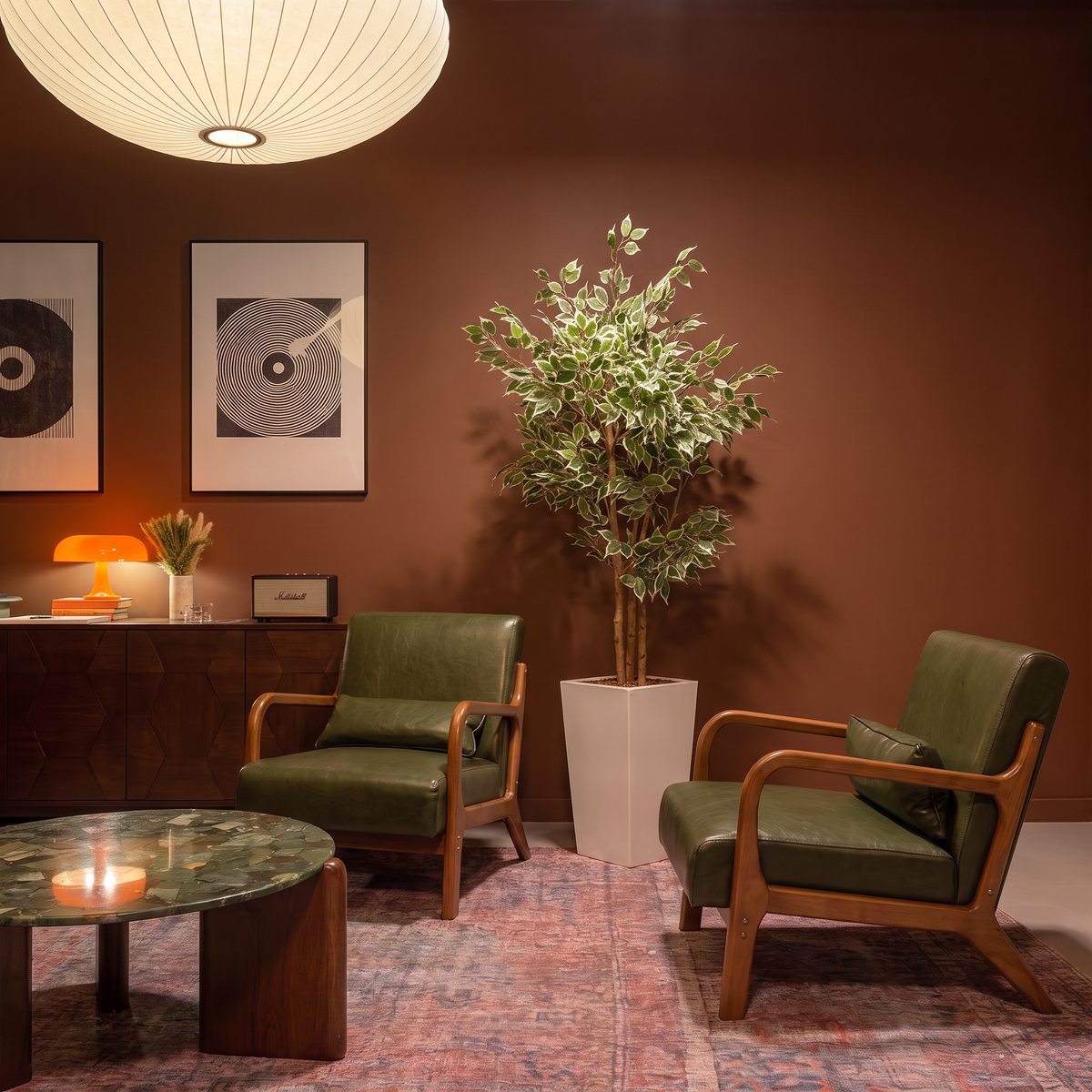 Kunst ficus benjamina 150 cm met decoratieve pot in zitkamer tussen twee groene leren fauteuils