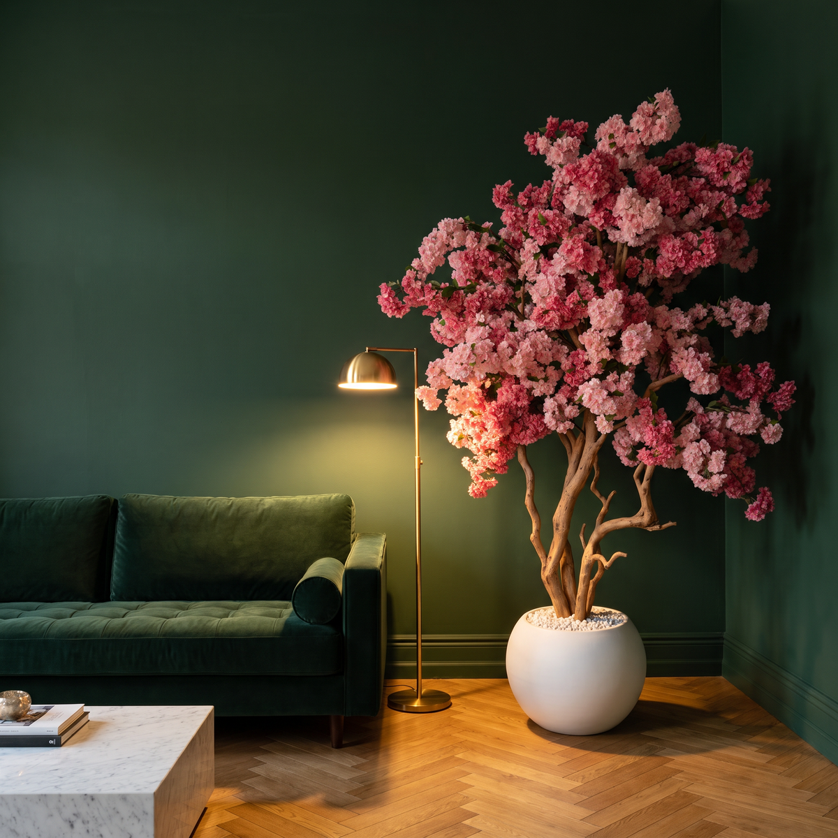 Kunst kersenbloesemboom roze in witte bolpot in een woonkamer met donkergroene muren, groene fluwelen bank en messing vloerlamp